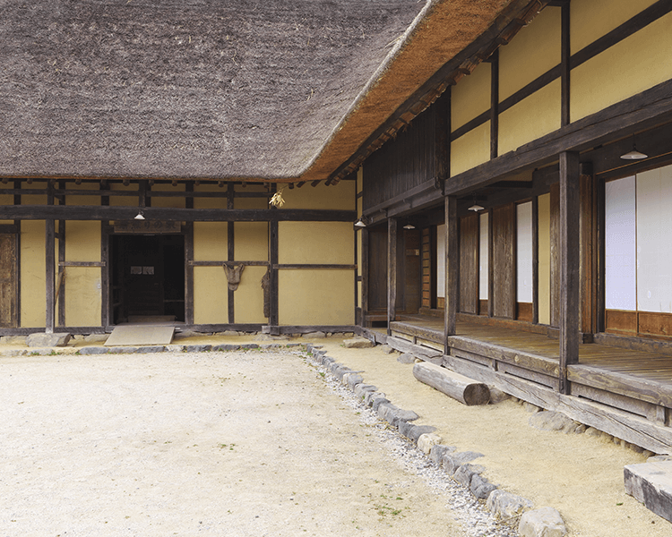 Looking from the courtyard, deep eaves and engawa surrounding the house are prominent in this traditional Japanese farm house. The house was built by a wealthy farmer in Tono, Iwate, in the late 19th century.